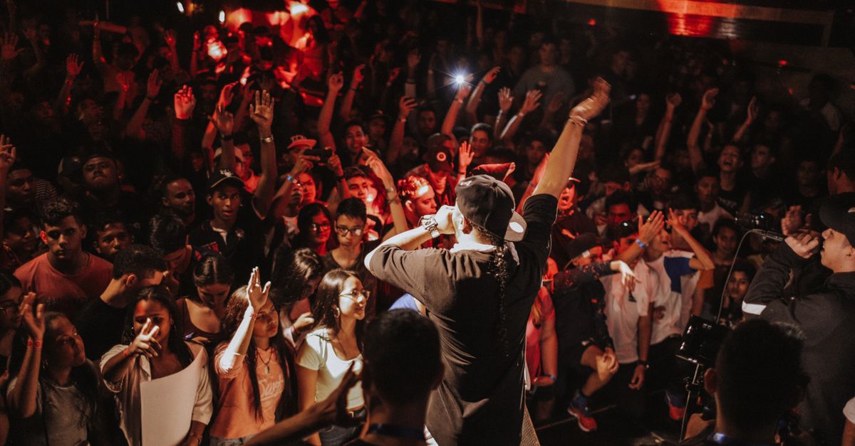 Vibrant rap concert with lively crowd and dynamic stage performance in a bustling nightclub atmosphere.